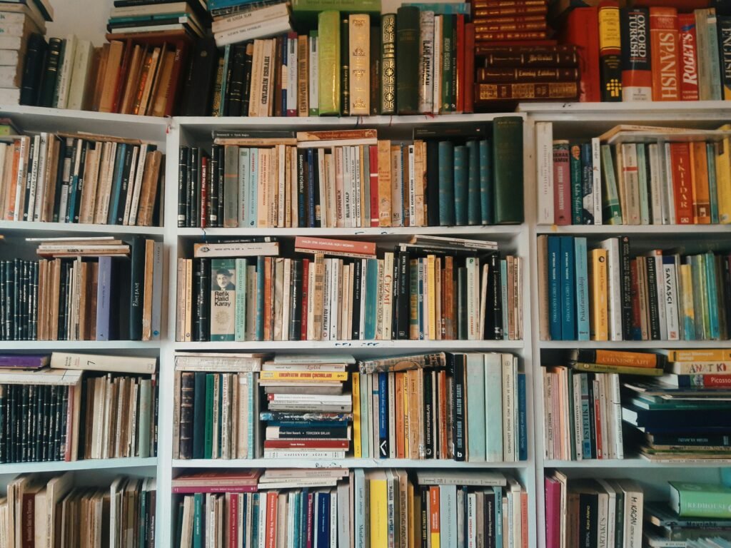 pexels-photo-7643400-7643400 A vast collection of books arranged on wooden shelves in a cozy library setting.